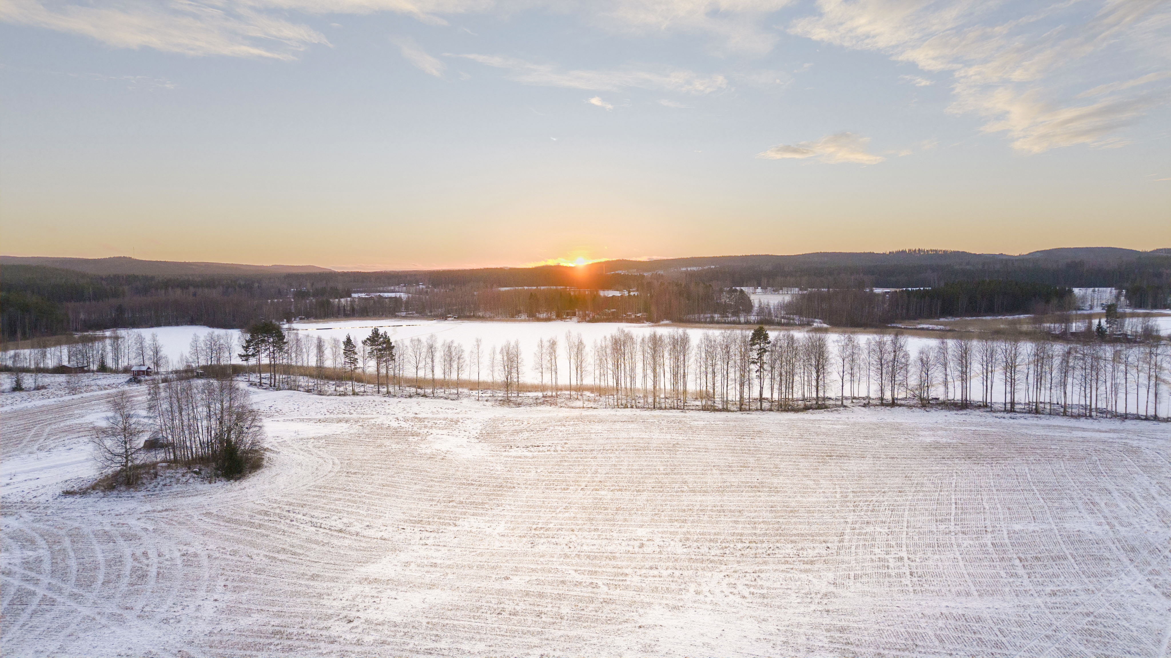 Aurinko laskee talvisessa Muhluniemessä.
