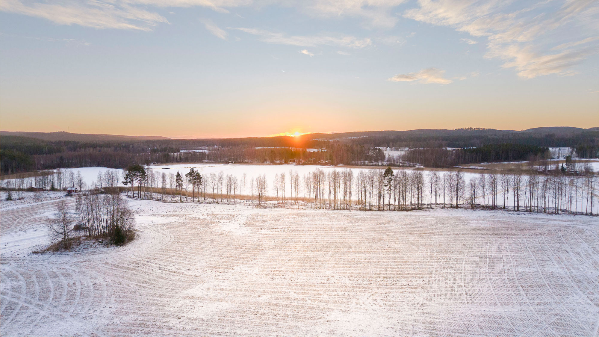 Aurinko laskee talvisessa Muhluniemessä.