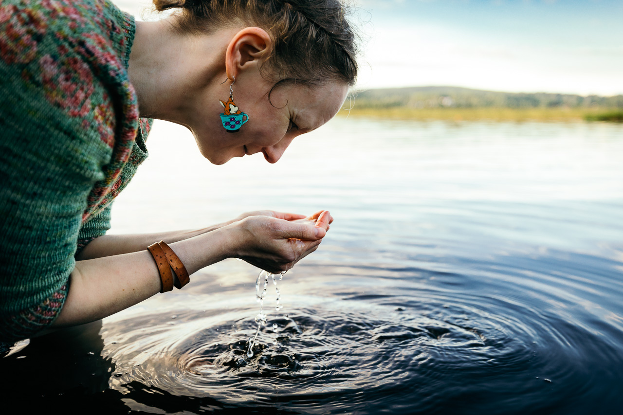 Nainen pesee kasvojaan järvessä.